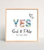 Quadratisches Poster mit den Namen des Brautpaars und dem Hochzeitsdatum. Oberhalb stehen die Buchstaben "YES". Die Buchstaben wurden ausgeschnitten und hinter ihnen scheinen Geldscheine hindurch.