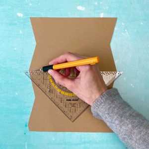 Eine Hand schneidet mit dem Skalpell mit Hilfe eines Geodreieck auf einer Karte.