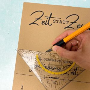 Hand schneidet mit Cutter und Geodreieck eine Karte mit dem Aufdruck „Zeit statt Zeug – Denn das schönste Geschenk ist gemeinsame Zeit“. Bastelidee für ein kleines, nachhaltiges Geschenk zu Weihnachten.