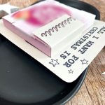 Nahaufnahme einer weihnachtlichen Druckvorlage mit dem Text „All I want for Christmas is You“. Eine kleine Schokoladenverpackung ist auf die Karte geklebt, dekoriert mit Sternen. Witzige Bastelidee für ein kleines Geschenk zu Weihnachten zum Selbermachen.