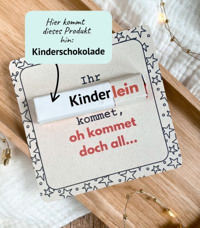 Kreative Weihnachts-Druckvorlage mit dem Spruch „Ihr Kinderlein kommet, oh kommet doch all…“. In die Karte wird eine Kinderschokolade gesteckt. Liebevoll fotografiert auf Holztablett mit Lichterkette – ideale Idee für ein kleines Wichtelgeschenk zu Weihnachten.