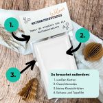 Schritt-für-Schritt-Anleitung mit nummerierten Pfeilen erklärt, wie man die Druckvorlage „Wellness statt Weihnachtsstress“ bastelt. Zeigt Materialien wie Gesichtsmaske, Schere und Tesafilm auf Holzuntergrund mit Weihnachtsdeko. Perfekte kleine Aufmerksamkeit im Advent.