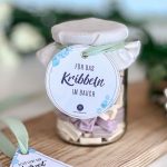 Nahaufnahme eines mit Brause gefüllten Glases und dem runden Anhänger mit der Aufschrift Für das Kribbeln im Bauch als originelle Idee für ein Geschenk zur Hochzeit DIY.