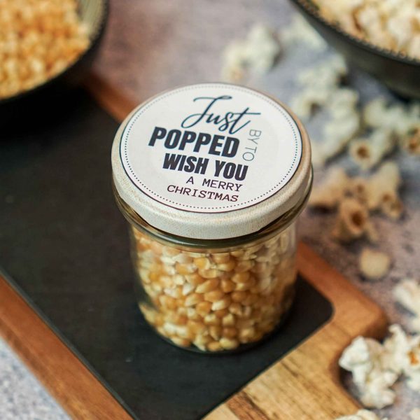 Einmachglas gefüllt mit Popcornmais und einem weihnachtlichen Aufkleber auf dem Deckel als kreatives Popcorn Geschenk.