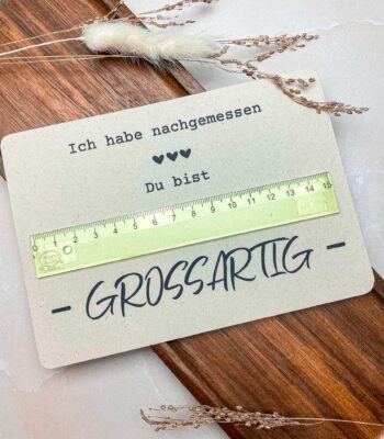 Die fertig gebastelte „Du bist großartig“-Karte mit Lineal liegt dekorativ auf einem Holztablett. Ein einfaches und kreatives DIY-Geschenk basierend auf einer digitalen Druckvorlage.