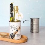Ein fertiges DIY Geburtstagsgeschenk in einer Dose, befüllt mit einer kleinen Flasche Sekt und einem Lindt Schokoriegel, dekoriert mit passendem Anhänger.
