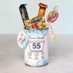 Eine farbenfroh befüllte Konservendose, verziert mit der Banderole "Schonend behandeln" für das Alter 55. Aus der Dose ragen verlockend Gummibärchen, ein bunter Lolli, Schokolade und eine Candy-Kette. Ein liebevoll arrangiertes DIY Geschenk zum runden Geburtstag. Lade dir einfach die PDF Vorlage herunter – so werden digitale Druckvorlagen zum ultimativen Last Minute Geschenk für Naschkatzen.