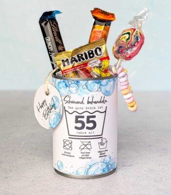 Eine farbenfroh befüllte Konservendose, verziert mit der Banderole "Schonend behandeln" für das Alter 55. Aus der Dose ragen verlockend Gummibärchen, ein bunter Lolli, Schokolade und eine Candy-Kette. Ein liebevoll arrangiertes DIY Geschenk zum runden Geburtstag. Lade dir einfach die PDF Vorlage herunter – so werden digitale Druckvorlagen zum ultimativen Last Minute Geschenk für Naschkatzen.